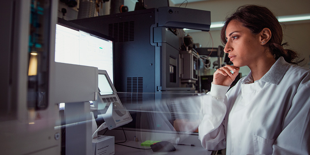Female scientist looks at a computer monitor next to research equipment