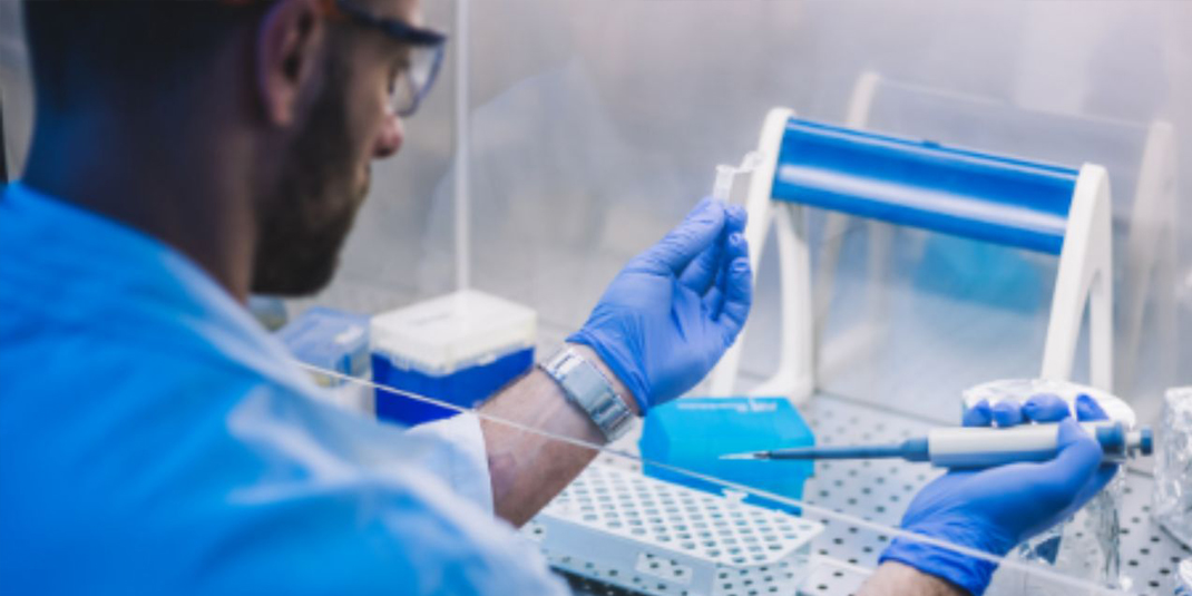 Lab technician pipetting reagent in centrifuge tube