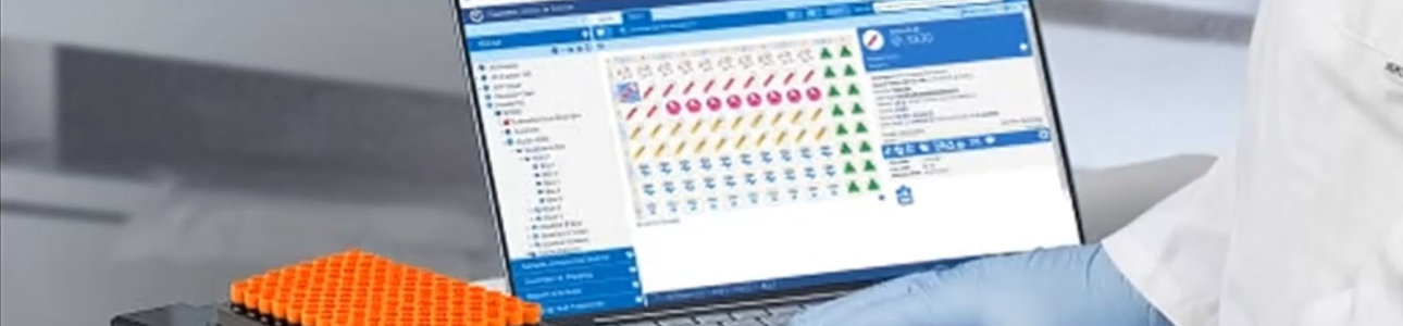 Computer screen showing FreezerPro being used by lab technician next to a rack of FluidX tubes